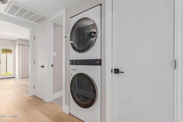 washroom with stacked washer / dryer, light wood-type flooring, and baseboards
