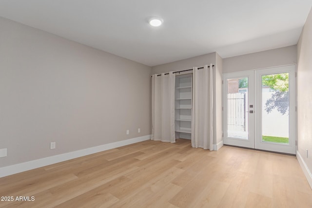 unfurnished bedroom featuring access to exterior, light wood finished floors, and baseboards