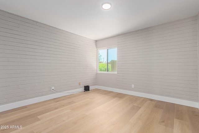spare room featuring baseboards and wood finished floors