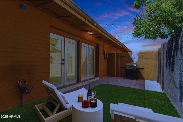 yard at dusk featuring french doors and a patio area