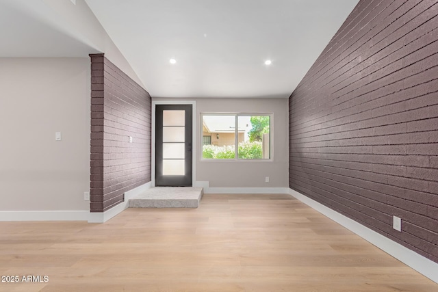unfurnished room with brick wall, an accent wall, baseboards, light wood-style flooring, and recessed lighting