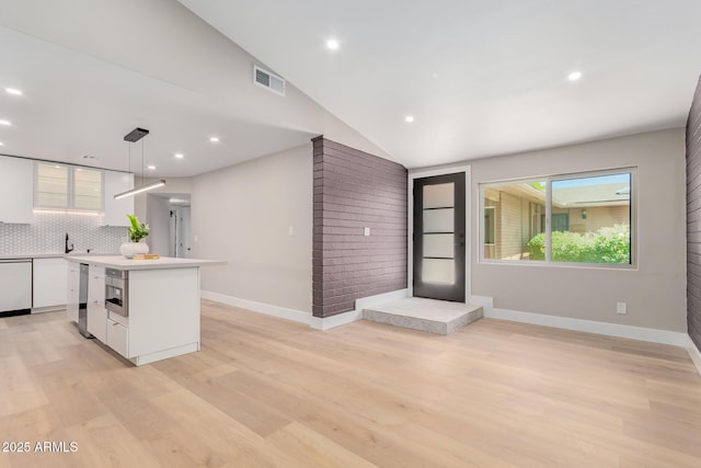 kitchen featuring white cabinetry, backsplash, light wood-style flooring, a center island, and vaulted ceiling
