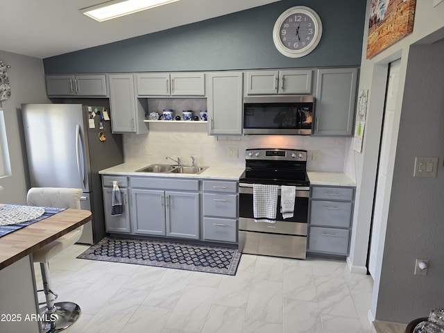 kitchen with appliances with stainless steel finishes, gray cabinets, and a sink