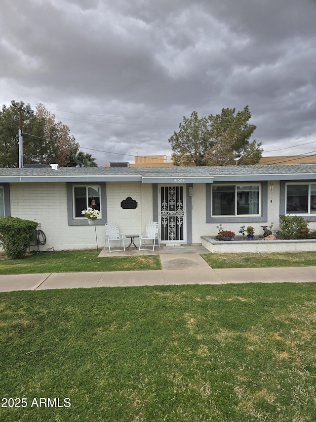 ranch-style house featuring concrete block siding and a front lawn