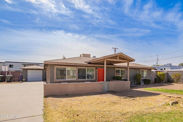 ranch-style home with stucco siding, concrete driveway, an attached garage, fence, and an outdoor structure