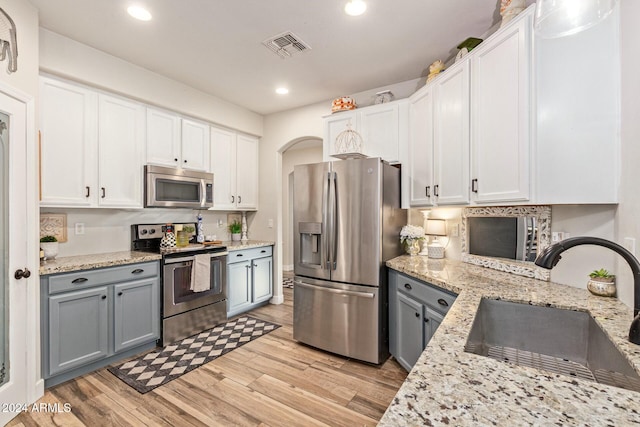 kitchen with white cabinets, sink, light hardwood / wood-style flooring, gray cabinets, and stainless steel appliances