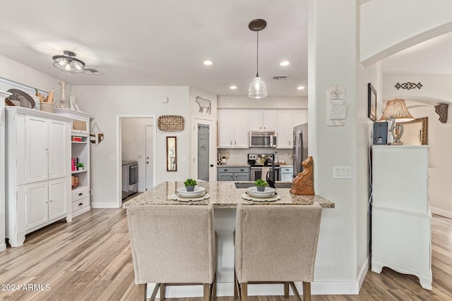 kitchen featuring kitchen peninsula, white cabinetry, light hardwood / wood-style flooring, and stainless steel appliances