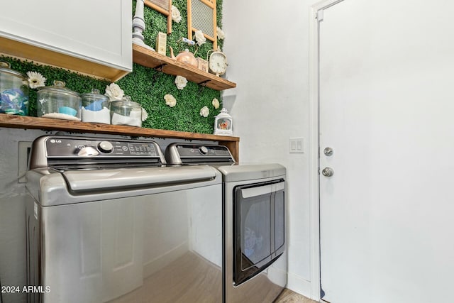 laundry room with cabinets, washing machine and dryer, and light hardwood / wood-style floors