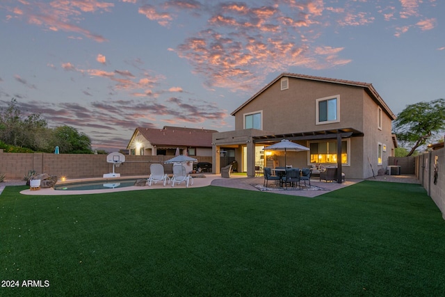 back house at dusk featuring a patio, central AC, and a lawn