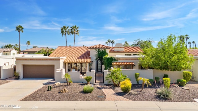 mediterranean / spanish house with a fenced front yard, stucco siding, a gate, a garage, and driveway