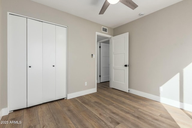 unfurnished bedroom featuring ceiling fan, light wood-type flooring, and a closet