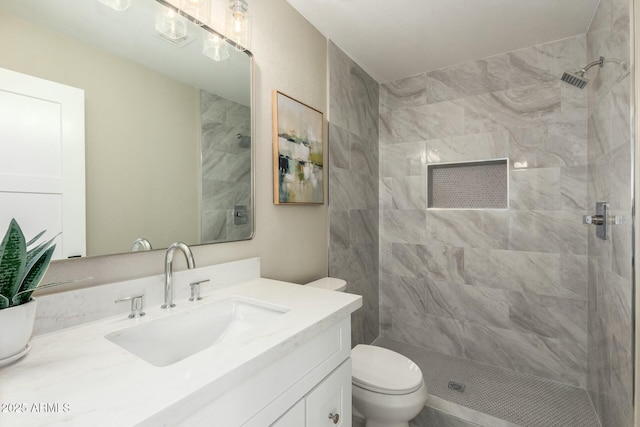 bathroom with vanity, toilet, and a tile shower