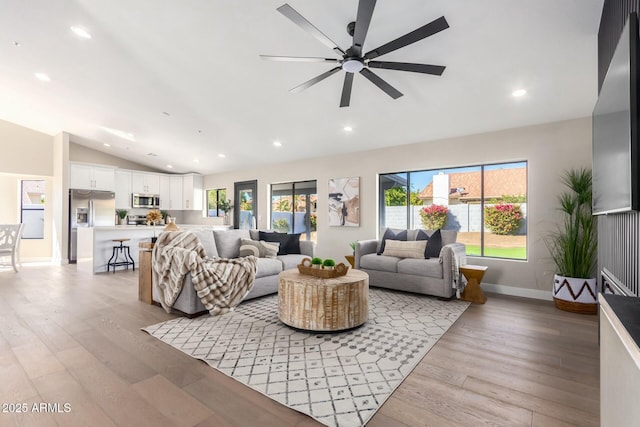 living room featuring ceiling fan, lofted ceiling, and light wood-type flooring