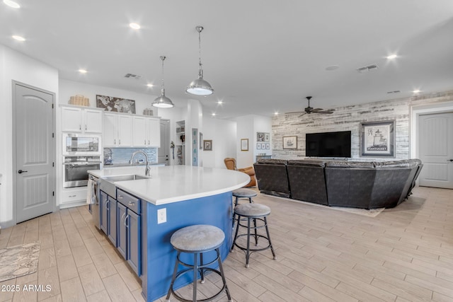 kitchen with sink, blue cabinetry, stainless steel appliances, white cabinets, and a kitchen bar