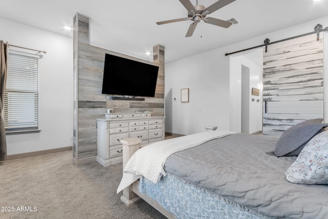 carpeted bedroom with ceiling fan, wooden walls, and a barn door