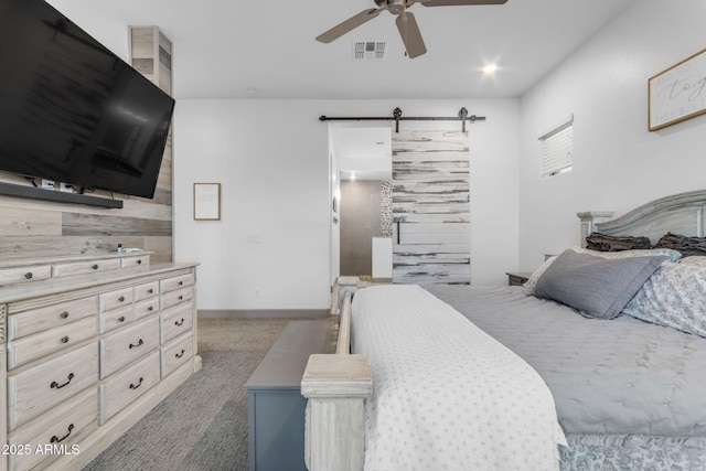 carpeted bedroom with ceiling fan and a barn door