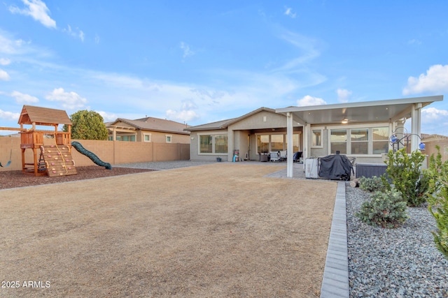 back of property featuring a playground and a patio