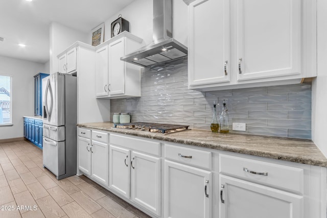 kitchen featuring white cabinetry, tasteful backsplash, light hardwood / wood-style flooring, stainless steel appliances, and wall chimney range hood