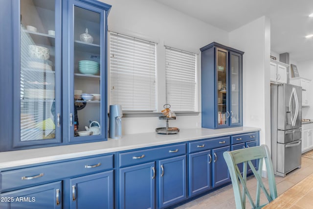 kitchen featuring light hardwood / wood-style floors, blue cabinets, and stainless steel fridge