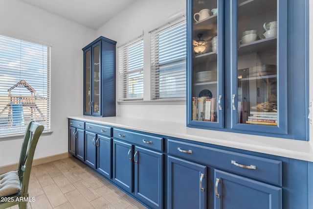 bar featuring blue cabinetry and light hardwood / wood-style flooring