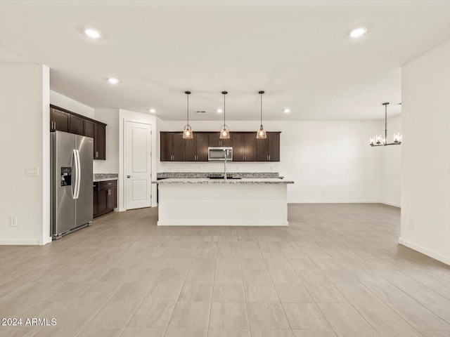 kitchen with pendant lighting, light hardwood / wood-style floors, light stone counters, stainless steel appliances, and a chandelier