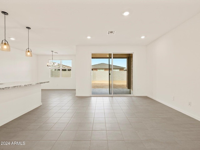 empty room featuring a chandelier and light tile patterned flooring