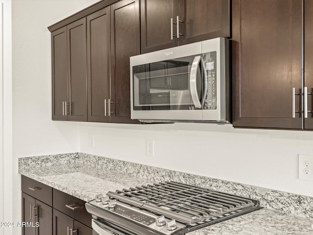 kitchen with appliances with stainless steel finishes, dark brown cabinetry, and light stone counters