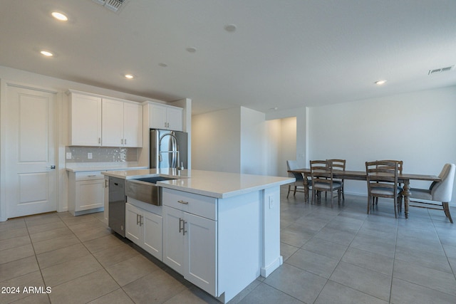 kitchen with white cabinets, an island with sink, light tile patterned flooring, sink, and appliances with stainless steel finishes