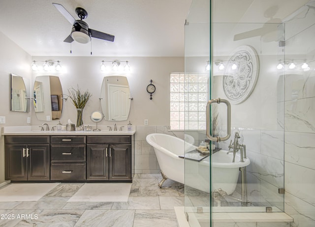 1217 S Longmore Ct, Chandler, AZ 85286 - bathroom featuring tile walls, ceiling fan, double vanity, a soaking tub, and marble finish floors