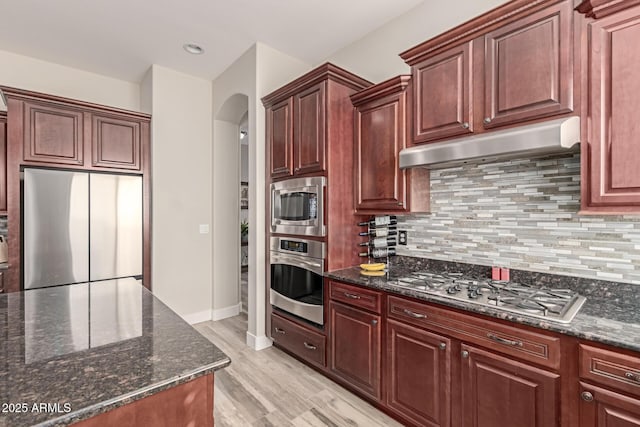 kitchen with dark stone countertops, tasteful backsplash, and appliances with stainless steel finishes