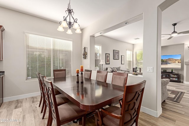 dining space featuring ceiling fan with notable chandelier and light hardwood / wood-style flooring