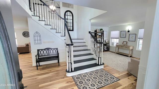 staircase with an inviting chandelier and light hardwood / wood-style floors