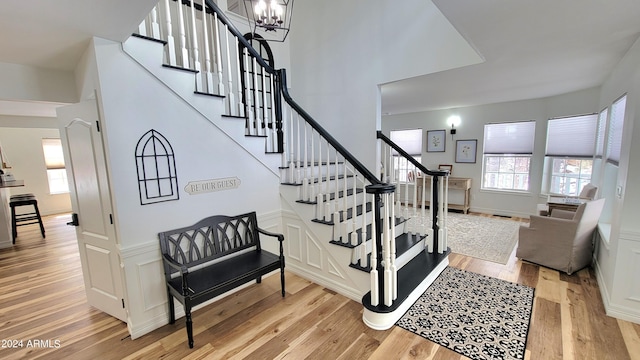 stairway with light wood-type flooring and a chandelier