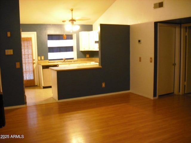 kitchen featuring a peninsula, visible vents, white cabinets, and wood finished floors