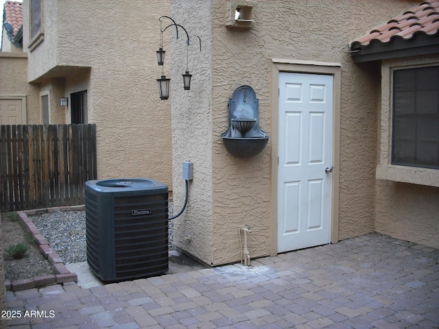 doorway to property with central AC, fence, a tiled roof, stucco siding, and a patio area