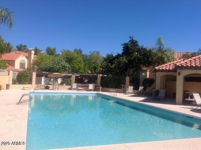 community pool with a patio area and fence