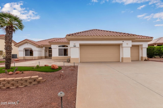 mediterranean / spanish home with a tile roof, an attached garage, concrete driveway, and stucco siding