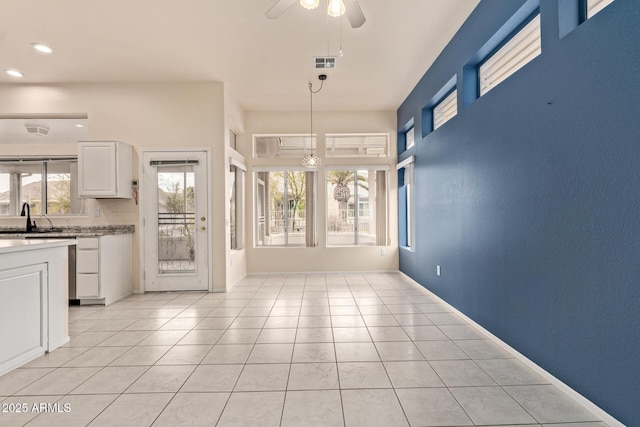 interior space with light tile patterned flooring, visible vents, baseboards, and a ceiling fan