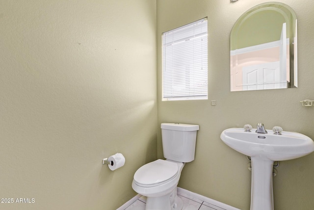 bathroom with a sink, baseboards, toilet, and tile patterned flooring