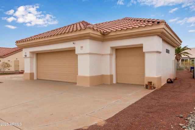 view of front of property with stucco siding, a tiled roof, and concrete driveway