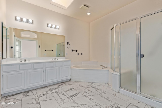 bathroom featuring a shower stall, a garden tub, a skylight, marble finish floor, and a sink