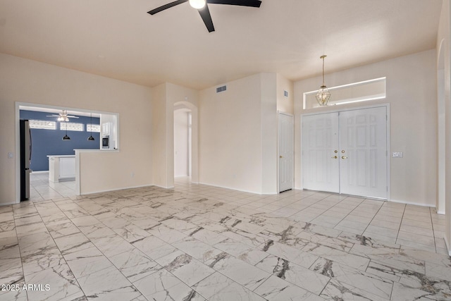 unfurnished living room featuring arched walkways, visible vents, marble finish floor, and ceiling fan