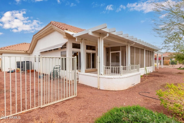 back of property featuring a tile roof, fence, and a sunroom