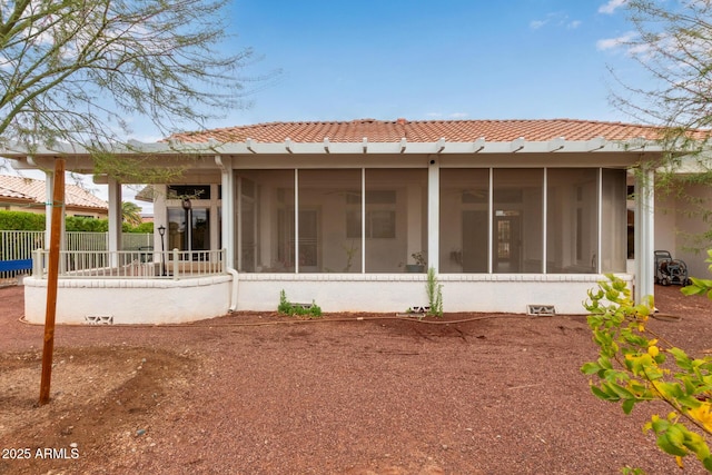 back of property featuring a tiled roof, a sunroom, and fence