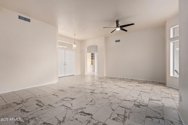 spare room featuring visible vents, arched walkways, marble finish floor, and a ceiling fan