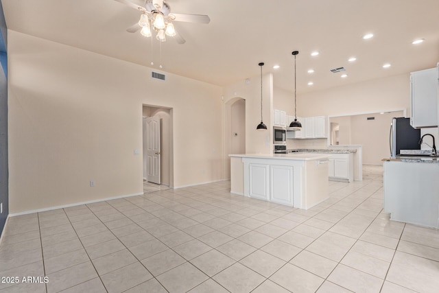 kitchen featuring visible vents, light countertops, arched walkways, stainless steel appliances, and a ceiling fan