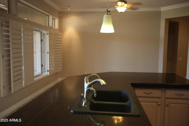 kitchen with dark countertops, ornamental molding, and a sink