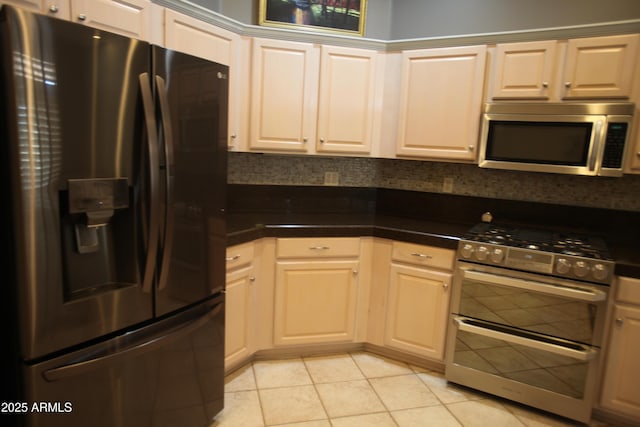 kitchen featuring stainless steel appliances, dark countertops, light tile patterned flooring, and tasteful backsplash