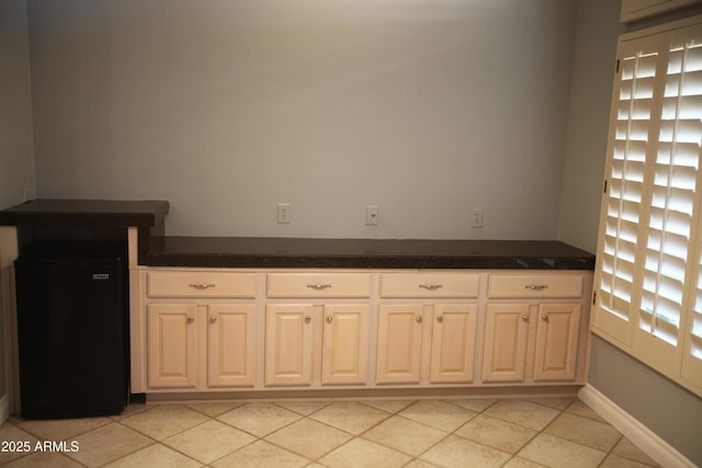 kitchen with dark countertops, light tile patterned floors, baseboards, and fridge