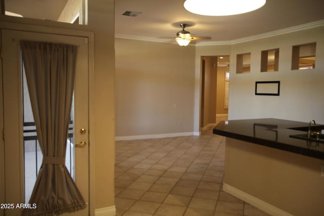 kitchen with dark countertops, visible vents, crown molding, and baseboards